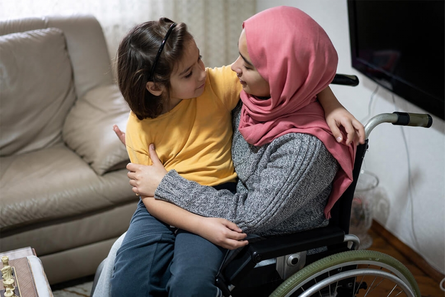 A young person in a wheelchair with a young person on her lap