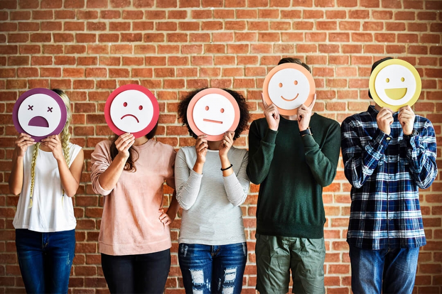 A group of 5 people holding emotive cut-outs over their faces