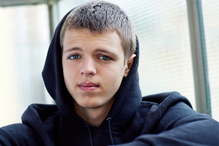 A young person looking into the camera with his hood half up