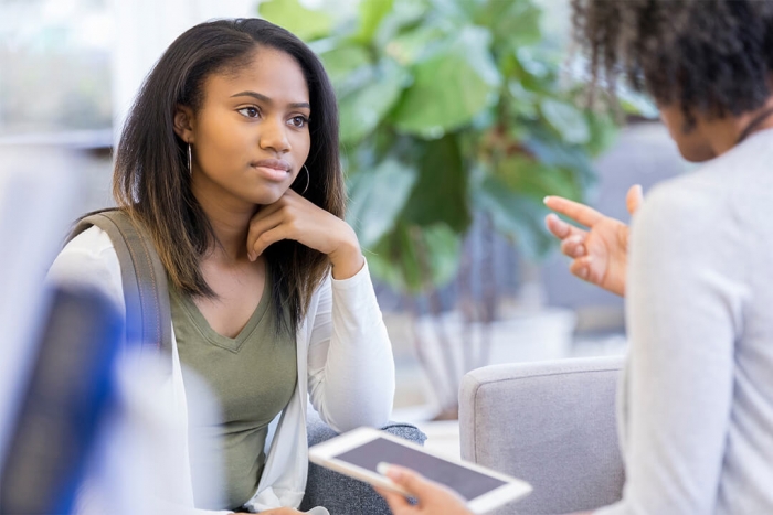 A young person in conversation with an adult, who is holding a tablet