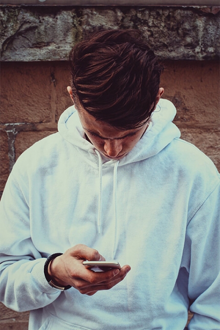 A young person looking down and using his mobile phone